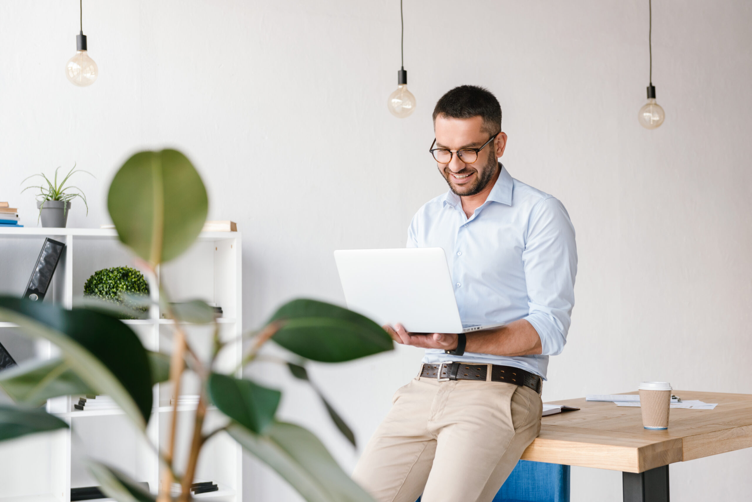 Smiling satisfied man 30s wearing white shirt sitting on table i